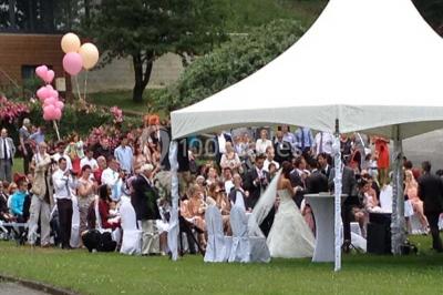 Des lanternes lumineuses flottent dans la nuit près d'une grande maison éclairée en bleu, entourée de personnes.