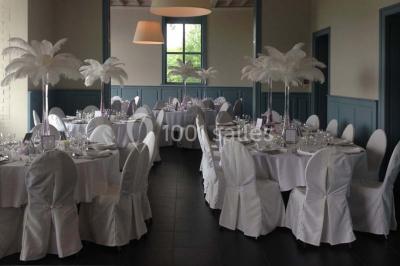 Des lanternes lumineuses flottent dans la nuit près d'une grande maison éclairée en bleu, entourée de personnes.