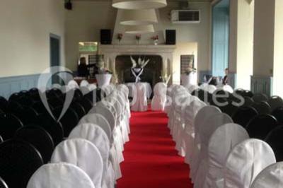 Des lanternes lumineuses flottent dans la nuit près d'une grande maison éclairée en bleu, entourée de personnes.