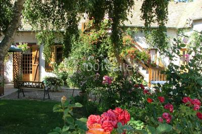 Chambre mansardée avec poutres apparentes, trois lits, une table et des chaises, éclairée par une fenêtre de toit.