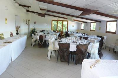 Chambre mansardée avec poutres apparentes, trois lits, une table et des chaises, éclairée par une fenêtre de toit.