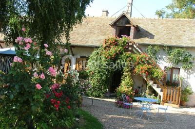 Chambre mansardée avec poutres apparentes, trois lits, une table et des chaises, éclairée par une fenêtre de toit.