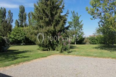 Chambre mansardée avec poutres apparentes, trois lits, une table et des chaises, éclairée par une fenêtre de toit.