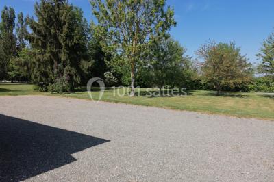 Chambre mansardée avec poutres apparentes, trois lits, une table et des chaises, éclairée par une fenêtre de toit.