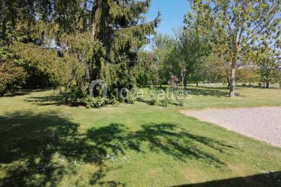Chambre mansardée avec poutres apparentes, trois lits, une table et des chaises, éclairée par une fenêtre de toit.