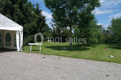 Chambre mansardée avec poutres apparentes, trois lits, une table et des chaises, éclairée par une fenêtre de toit.