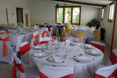 Chambre mansardée avec poutres apparentes, trois lits, une table et des chaises, éclairée par une fenêtre de toit.