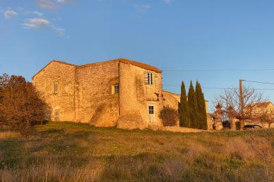 Dîner en plein air de nuit avec des guirlandes lumineuses, des invités assis autour de tables dans une cour en pierre.