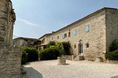 Dîner en plein air de nuit avec des guirlandes lumineuses, des invités assis autour de tables dans une cour en pierre.