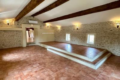 Dîner en plein air de nuit avec des guirlandes lumineuses, des invités assis autour de tables dans une cour en pierre.