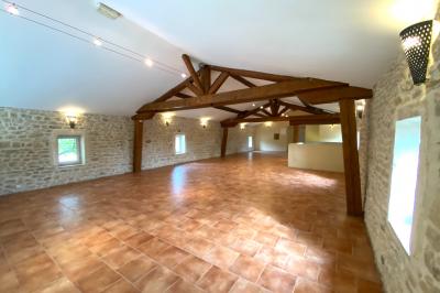 Dîner en plein air de nuit avec des guirlandes lumineuses, des invités assis autour de tables dans une cour en pierre.