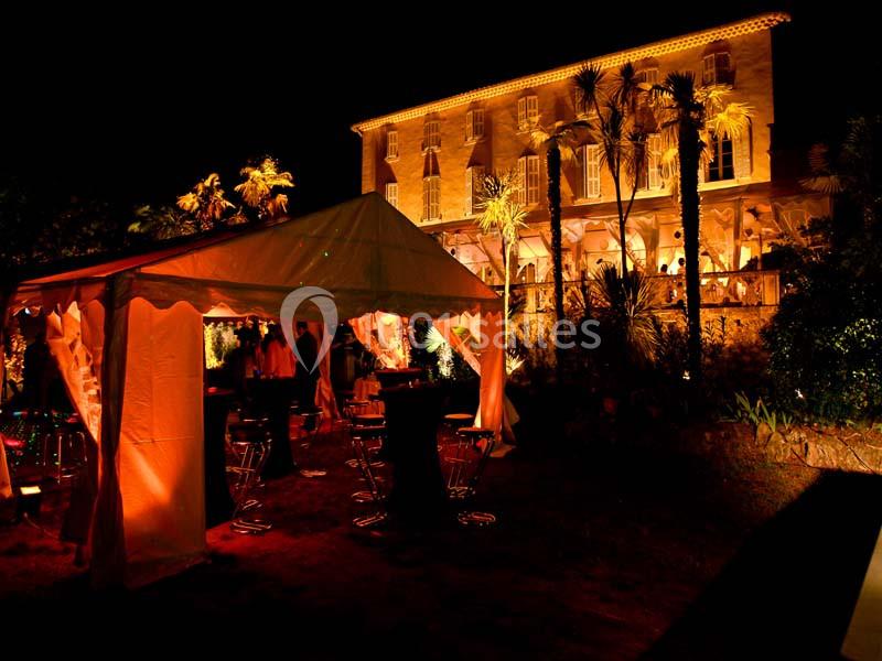 Tente éclairée et bâtiment illuminé en arrière-plan lors d'un événement nocturne en extérieur.