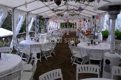 Un couple en tenue de mariage se tient la main en marchant dans un vignoble verdoyant.