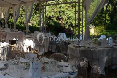 Un couple en tenue de mariage se tient la main en marchant dans un vignoble verdoyant.