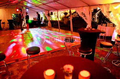 Un couple en tenue de mariage se tient la main en marchant dans un vignoble verdoyant.