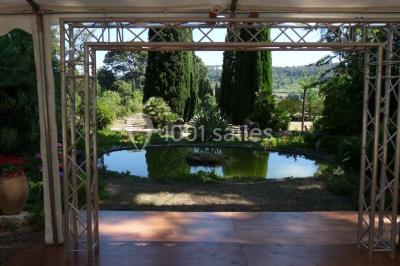 Un couple en tenue de mariage se tient la main en marchant dans un vignoble verdoyant.