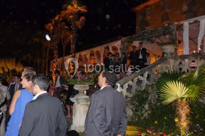 Un couple en tenue de mariage se tient la main en marchant dans un vignoble verdoyant.
