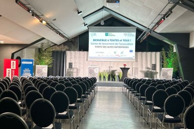 Salle avec grandes baies vitrées donnant sur une piste extérieure, aménagée avec tables, chaises et fauteuils rouges.