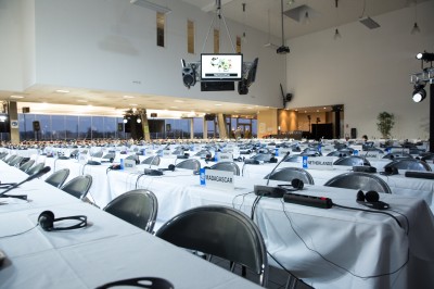 Salle avec grandes baies vitrées donnant sur une piste extérieure, aménagée avec tables, chaises et fauteuils rouges.