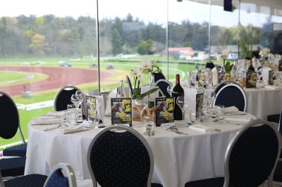 Salle avec grandes baies vitrées donnant sur une piste extérieure, aménagée avec tables, chaises et fauteuils rouges.