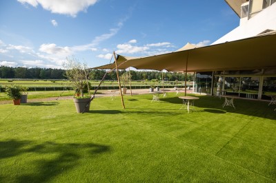 Salle avec grandes baies vitrées donnant sur une piste extérieure, aménagée avec tables, chaises et fauteuils rouges.