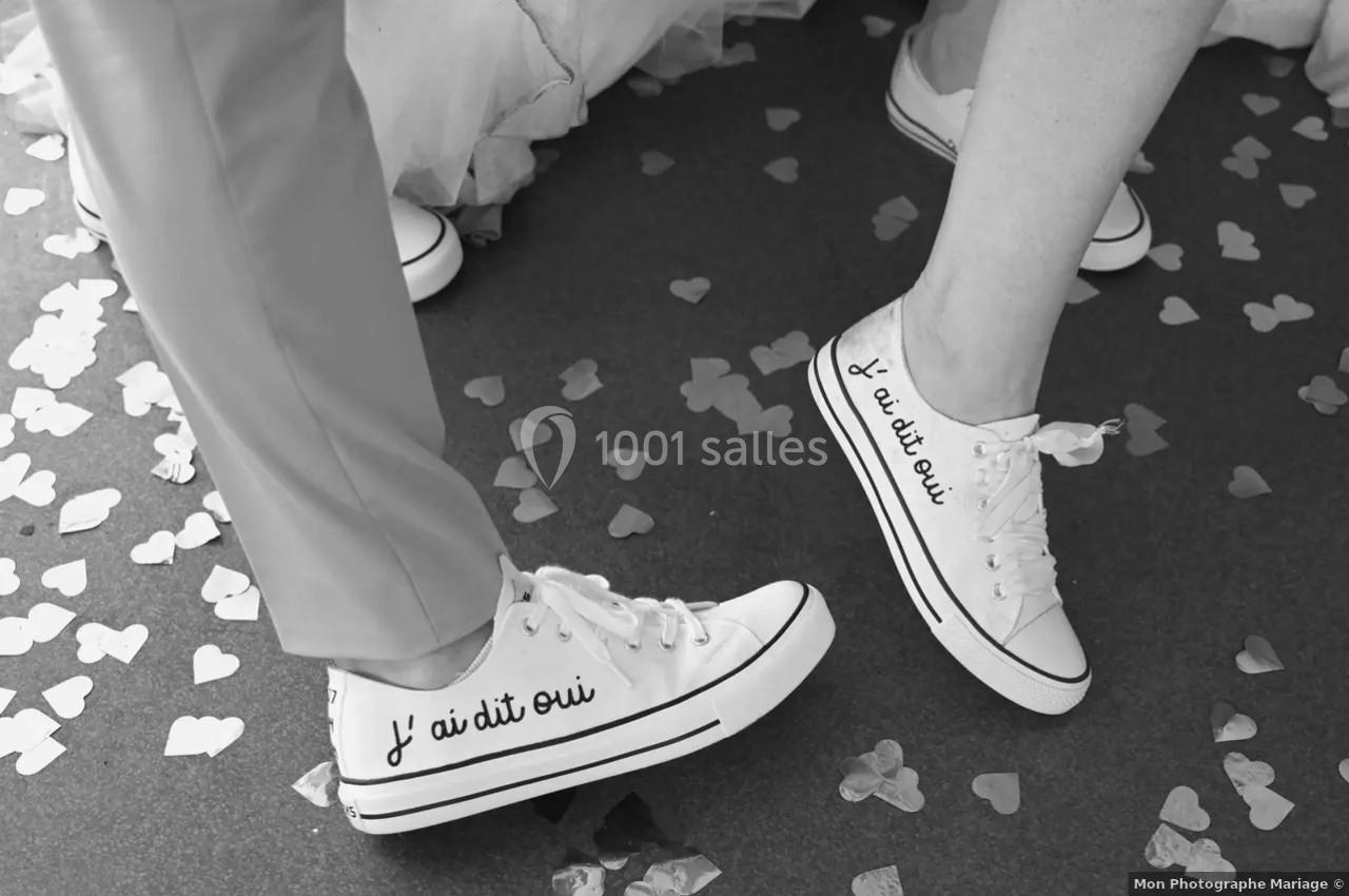 Deux personnes portant des baskets blanches avec l'inscription ’J'ai dit oui’, entourées de confettis en forme de cœur.