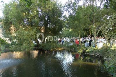 Façade d'un bâtiment en pierre éclairée la nuit, avec des portes vitrées et des chaises disposées sur une pelouse.