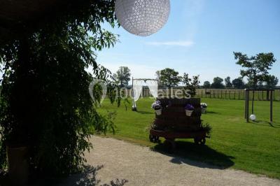 Salle de réception décorée avec des nappes blanches et des rubans rouges, tables ornées de centres de table fleuris.