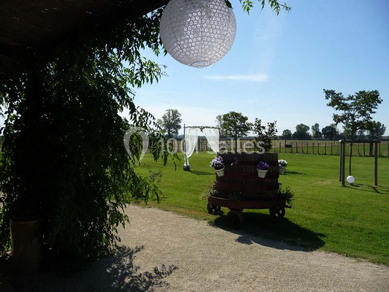 Un jardin verdoyant avec une balançoire décorée et un chariot fleuri sous un ciel dégagé.