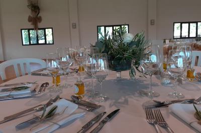 Salle de réception décorée avec des nappes blanches et des rubans rouges, tables ornées de centres de table fleuris.