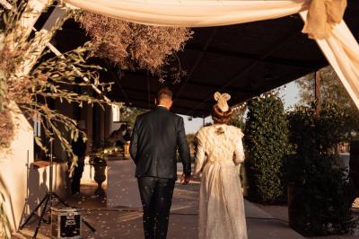Salle de réception décorée avec des nappes blanches et des rubans rouges, tables ornées de centres de table fleuris.