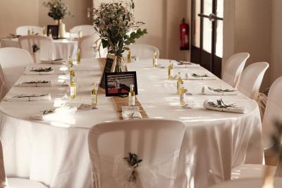 Salle de réception décorée avec des nappes blanches et des rubans rouges, tables ornées de centres de table fleuris.