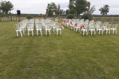 Salle de réception décorée avec des nappes blanches et des rubans rouges, tables ornées de centres de table fleuris.