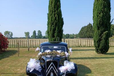 Salle de réception décorée avec des nappes blanches et des rubans rouges, tables ornées de centres de table fleuris.
