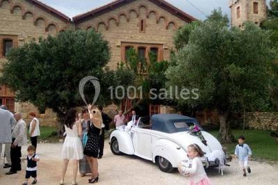 Église en pierre avec une tour, entourée de végétation et éclairée par une lumière naturelle sous un ciel bleu.