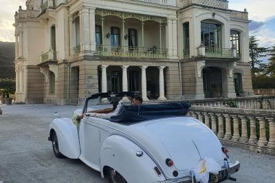 Église en pierre avec une tour, entourée de végétation et éclairée par une lumière naturelle sous un ciel bleu.