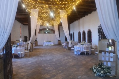 Église en pierre avec une tour, entourée de végétation et éclairée par une lumière naturelle sous un ciel bleu.