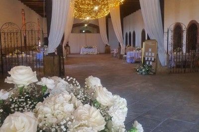 Église en pierre avec une tour, entourée de végétation et éclairée par une lumière naturelle sous un ciel bleu.