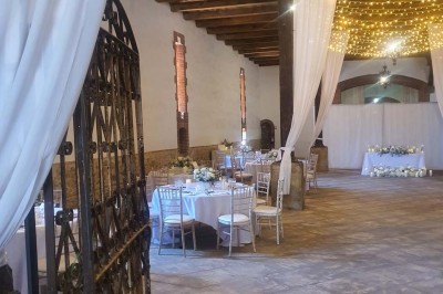 Église en pierre avec une tour, entourée de végétation et éclairée par une lumière naturelle sous un ciel bleu.