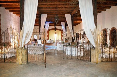 Église en pierre avec une tour, entourée de végétation et éclairée par une lumière naturelle sous un ciel bleu.