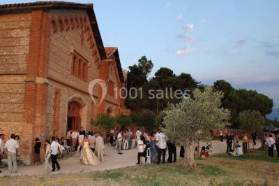 Église en pierre avec une tour, entourée de végétation et éclairée par une lumière naturelle sous un ciel bleu.