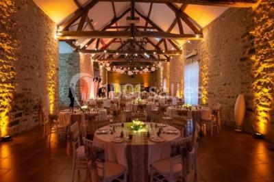 Une mariée en robe blanche applaudit devant un groupe de personnes dans un jardin lors d'une célébration.