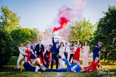 Une mariée en robe blanche applaudit devant un groupe de personnes dans un jardin lors d'une célébration.