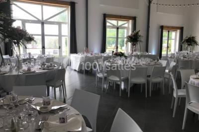 Une mariée en robe blanche applaudit devant un groupe de personnes dans un jardin lors d'une célébration.