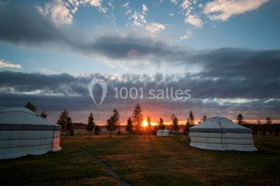 Une mariée en robe blanche applaudit devant un groupe de personnes dans un jardin lors d'une célébration.