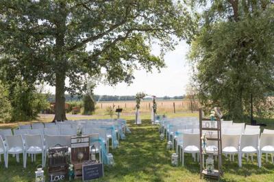 Une mariée en robe blanche applaudit devant un groupe de personnes dans un jardin lors d'une célébration.