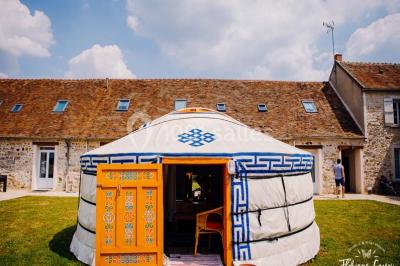 Une mariée en robe blanche applaudit devant un groupe de personnes dans un jardin lors d'une célébration.