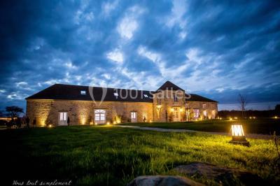Une mariée en robe blanche applaudit devant un groupe de personnes dans un jardin lors d'une célébration.