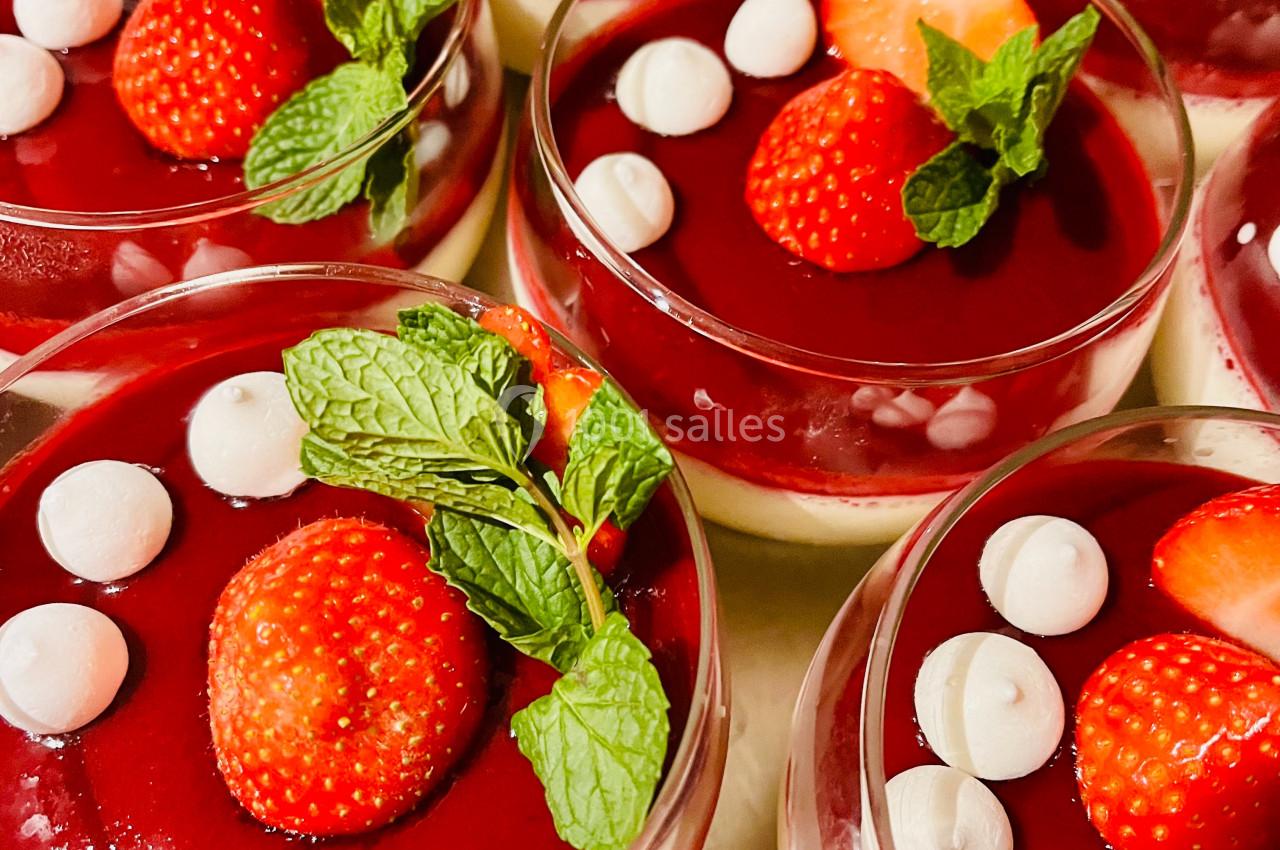 Desserts en verrines composés de coulis rouge, fraises fraîches, feuilles de menthe et petites meringues blanches.
