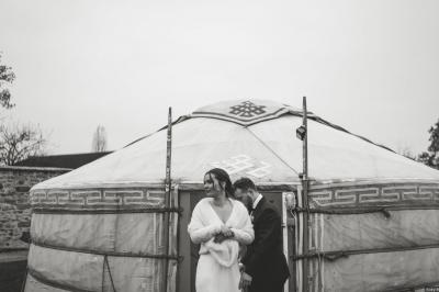 Une mariée en robe blanche applaudit devant un groupe de personnes dans un jardin lors d'une célébration.